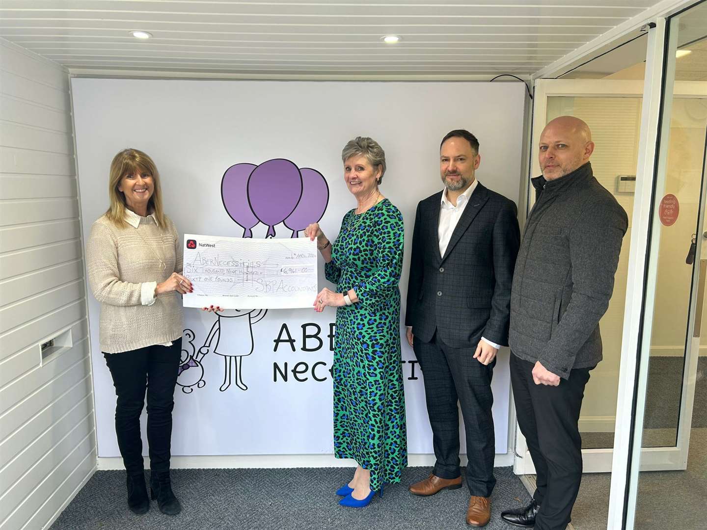Sandra Stephen, Stuart Beaton, and Stephen Glanas from SBP present the donation to Michelle Herd, Co-founder and CEO of AberNecessities.